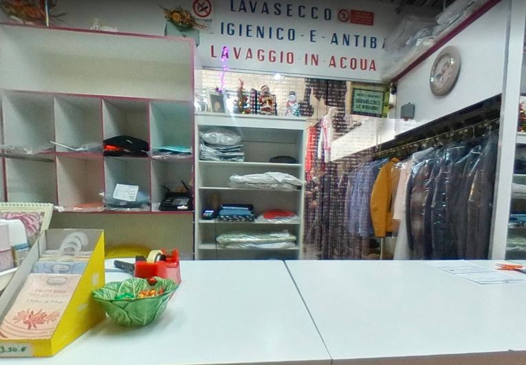Interno di Lavanderia Del Corso con banco, scaffali e capi pronti